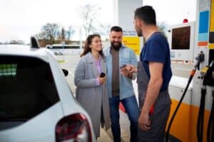 Gas station attendant and two customers talking beside the fuel pumps