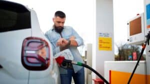 Driver checking his watch while refueling at a gas station pump