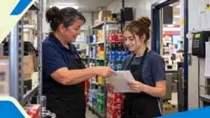 Store manager showing a new employee a training checklist in the stockroom
